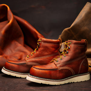 Brown leather boots with white soles on a dark background