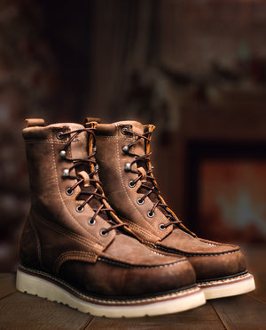 Pair of brown leather boots on a wooden surface with a blurred background
